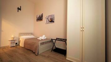 A bedroom with a bed, a nightstand, a wardrobe, and two wall-mounted pictures.