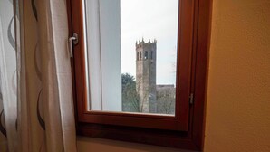 Una mesa de comedor con un plato, cubiertos y una copa, con vistas a una torre por la ventana.