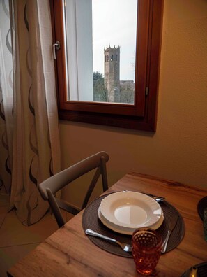 Een eettafel met een bord, bestek en een glas, met uitzicht op een toren.