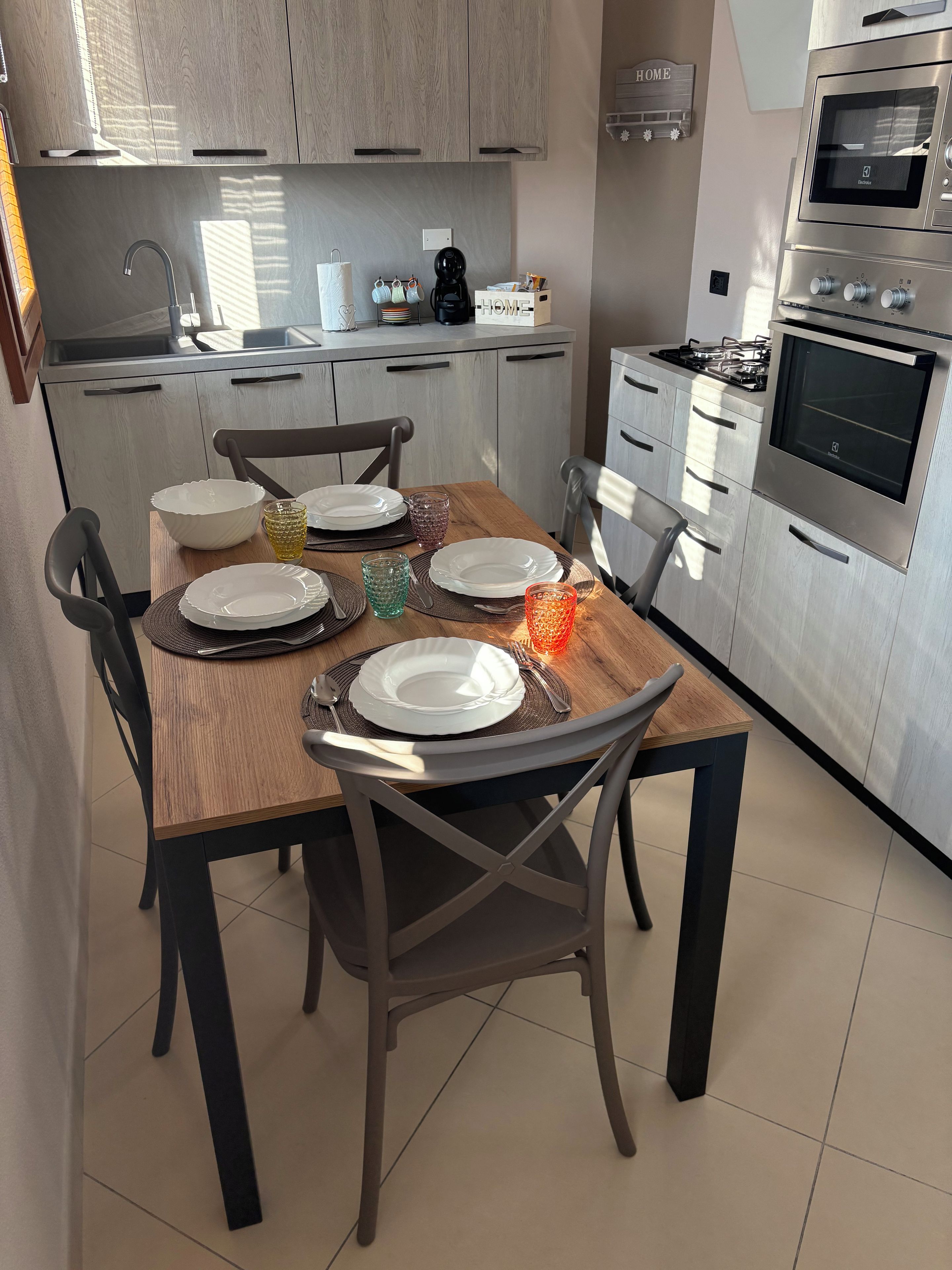 Una cocina moderna con armarios de madera, una mesa de comedor preparada para cuatro personas y electrodomésticos integrados.