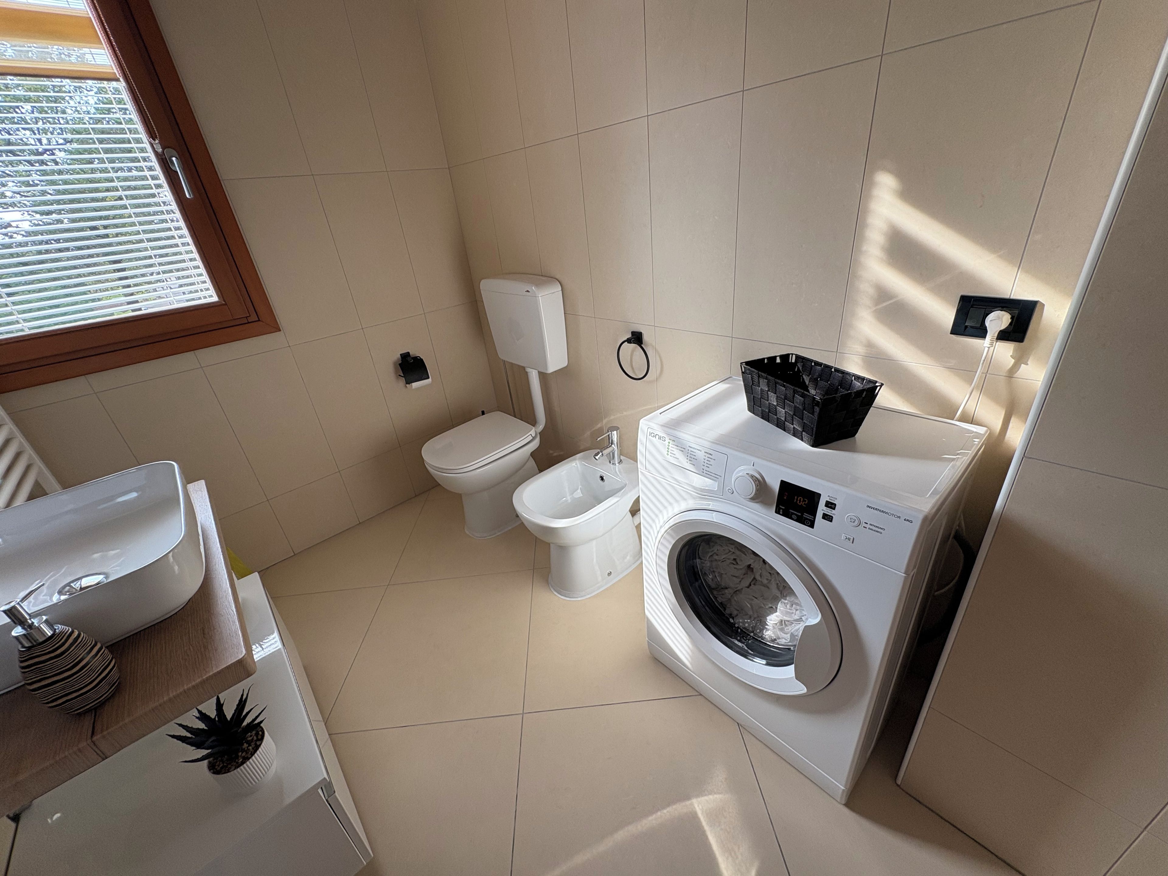 Un bagno compatto con il water, un lavandino e una lavatrice.