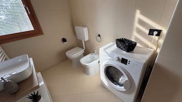 Un bagno compatto con il water, un lavandino e una lavatrice.