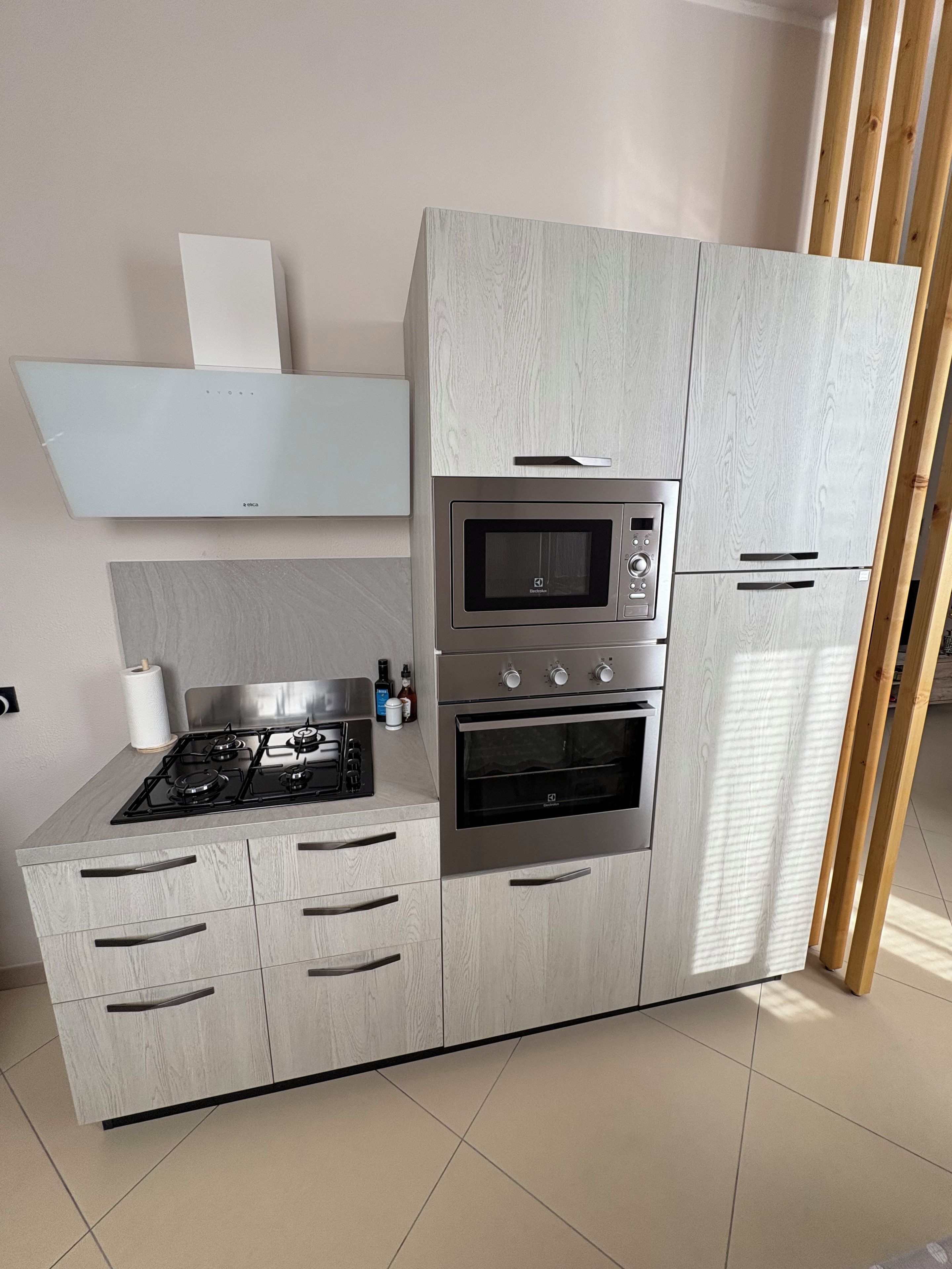 Een moderne keuken met een ingebouwde magnetron, oven en gasfornuis.