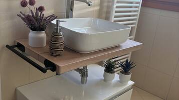 A modern bathroom with a large rectangular sink, a mirror, and a towel rack.