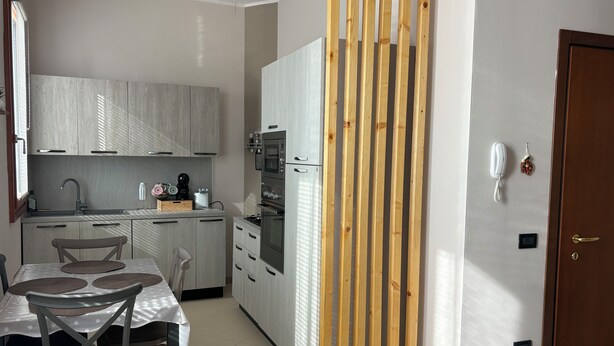 Una cocina moderna con comedor, que presenta un separador de madera, un refrigerador y un lavamanos.