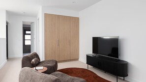 Una sala de estar moderna con un televisor de pantalla plana, un armario espacioso y una zona de estar acogedora.