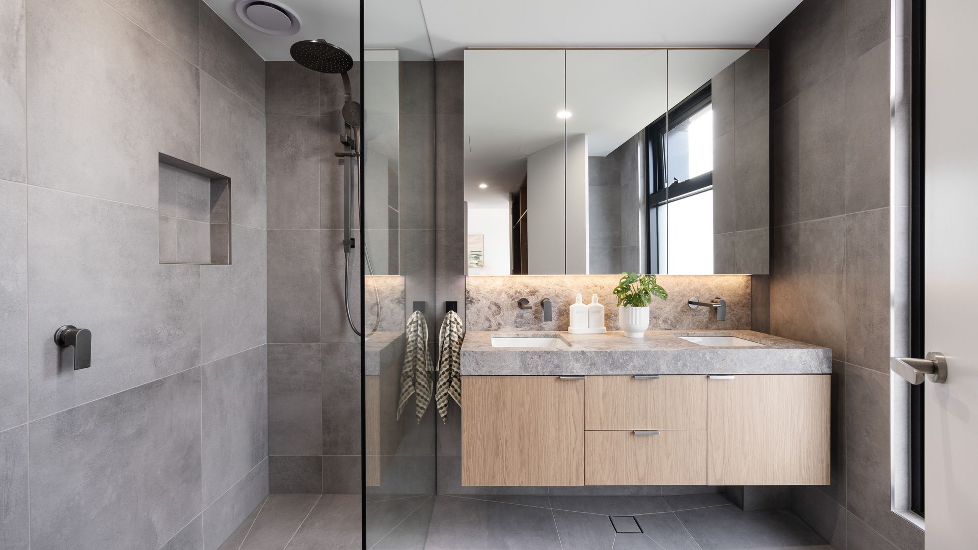 A modern bathroom with a glass-enclosed shower, a vanity with a sink, and a large mirror.