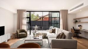A modern living room with a sofa, coffee table, and TV. - The Nova - Caulfield South (Caulfield South)