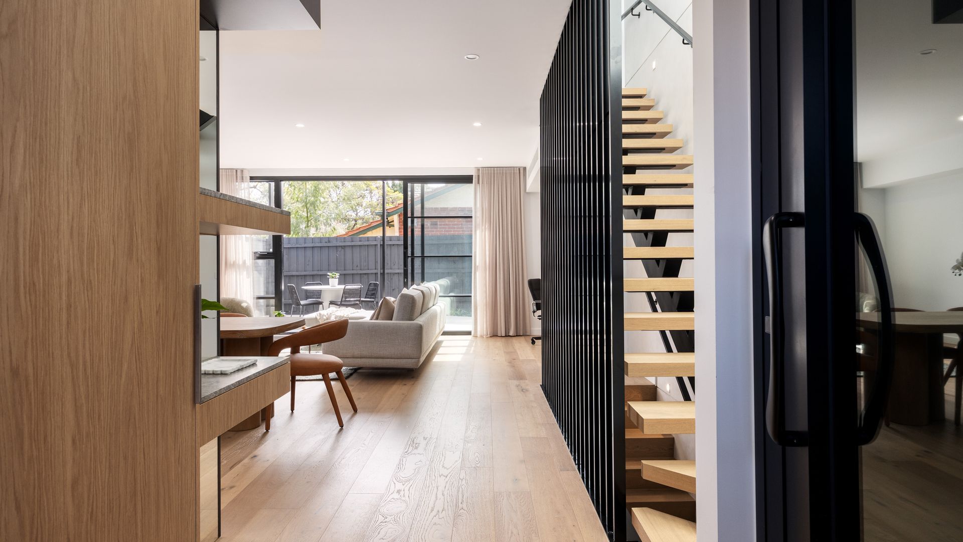 A modern interior with a kitchen, dining area, and a staircase leading to an upper level.