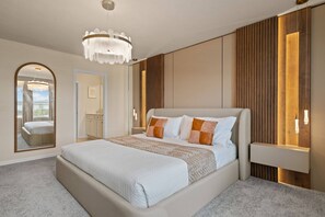 A modern bedroom with a large bed, a chandelier, and a mirror. - 5BR Townhouse Sleeps 14 With Game Room (Clermont)