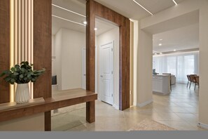 A modern interior with a wooden bench, a potted plant, and a kitchen area with a dining set. - 5BR Townhouse Sleeps 14 With Game Room (Clermont)