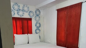 A bedroom with a bed, white curtains, and a patterned wall.