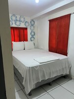 A bedroom with a bed, white curtains, and a patterned wall.
