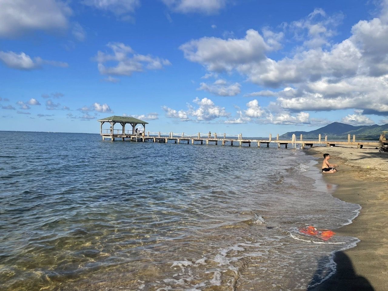 A pier extending into calm waters with a clear sky above.