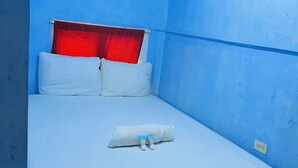 A single bed with white bedding, a red headboard, and a white pillow.