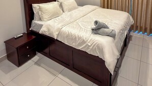 A modern hotel room with a large bed, a nightstand, and a curtain. - Luxury 3-Bedroom Condo in Tranquil Accra with Pool and Fitness Room (Accra)