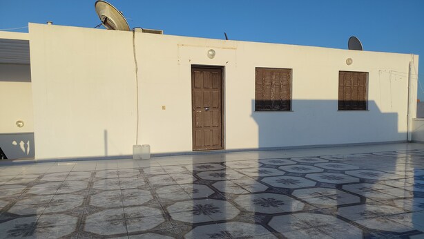A building with a flat roof, a door, and two windows with shutters. - Studio Amine  (Mahdia)