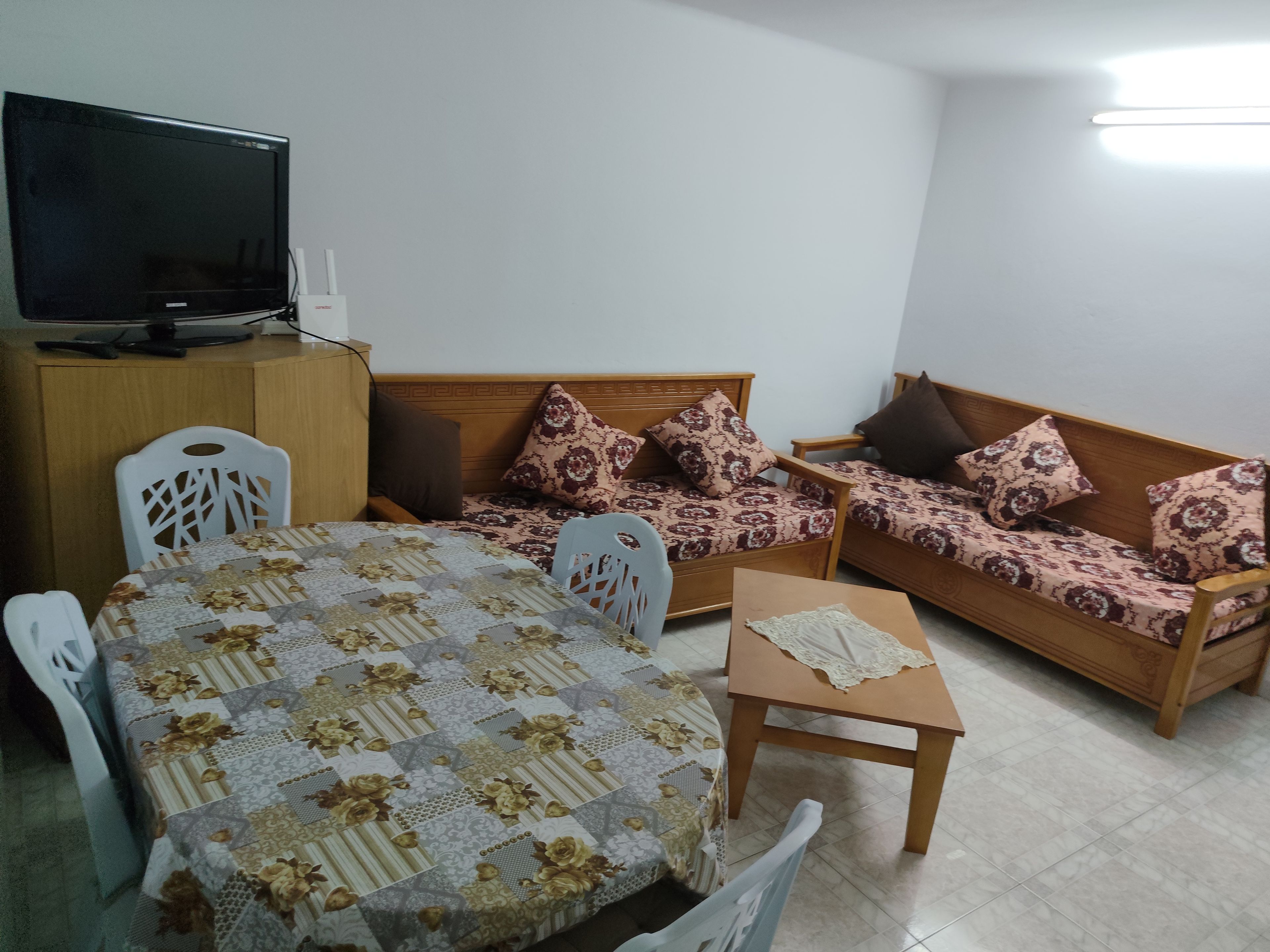 A living room with a sofa, a table, a television, and a cabinet.