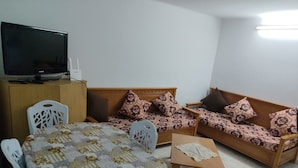 A living room with a sofa, a table, a television, and a cabinet. - Studio Amine  (Mahdia)