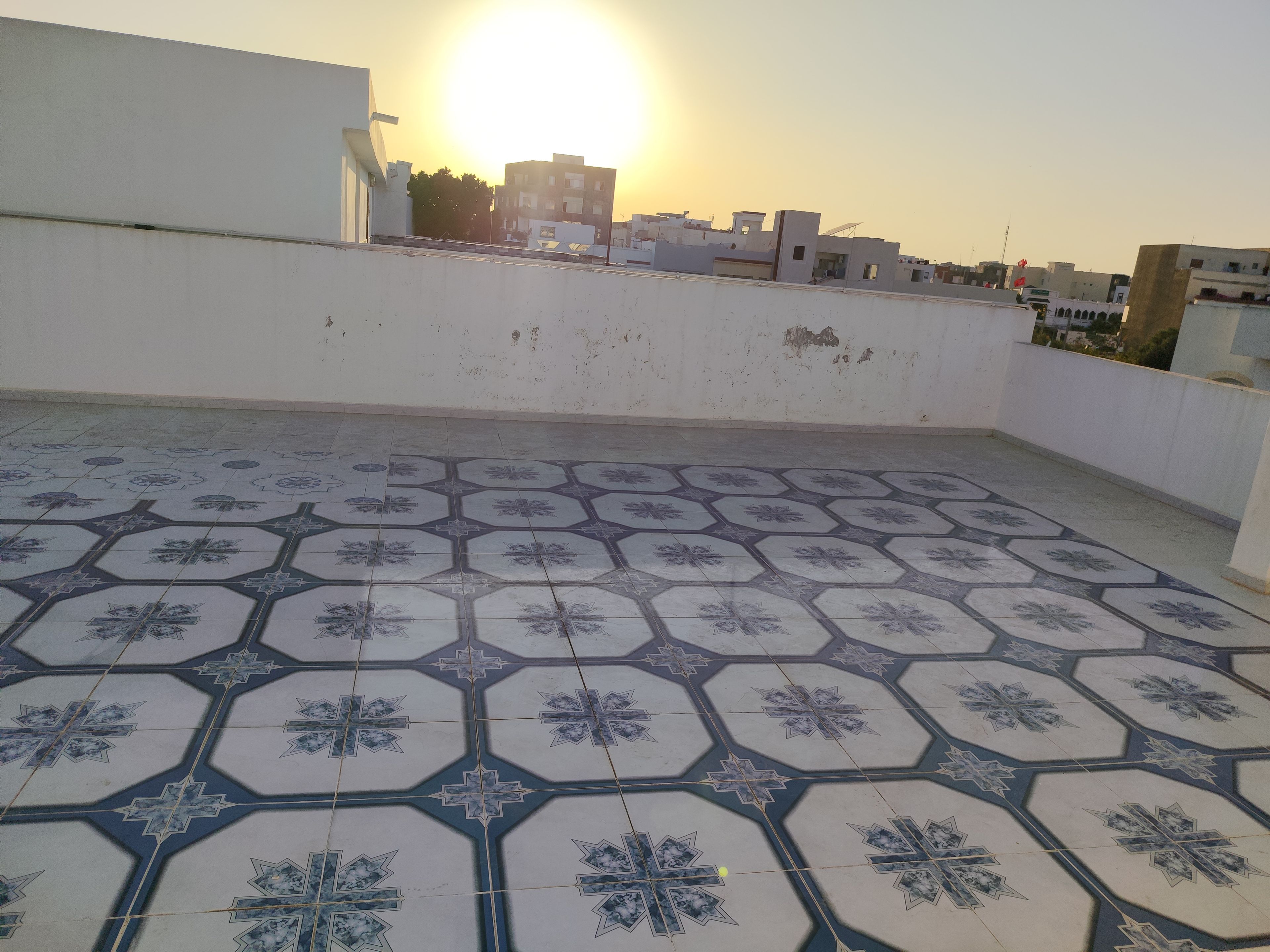 Una terraza en la azotea con baldosas estampadas y vistas a edificios a lo lejos.
