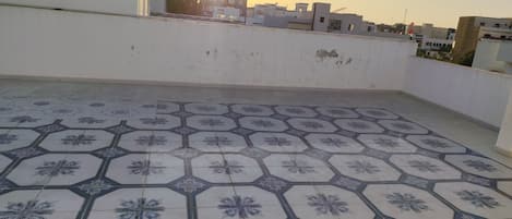 Eine Dachterrasse mit gemusterten Fliesen und Blick auf Gebäude in der Ferne.