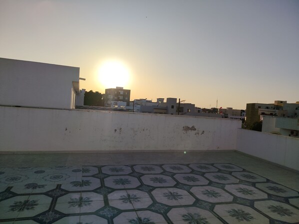 Una terraza en la azotea con suelo estampado y vistas a edificios al atardecer.