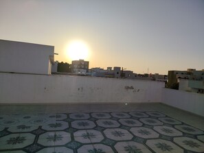 Una terraza en la azotea con suelo estampado y vistas a edificios al atardecer.