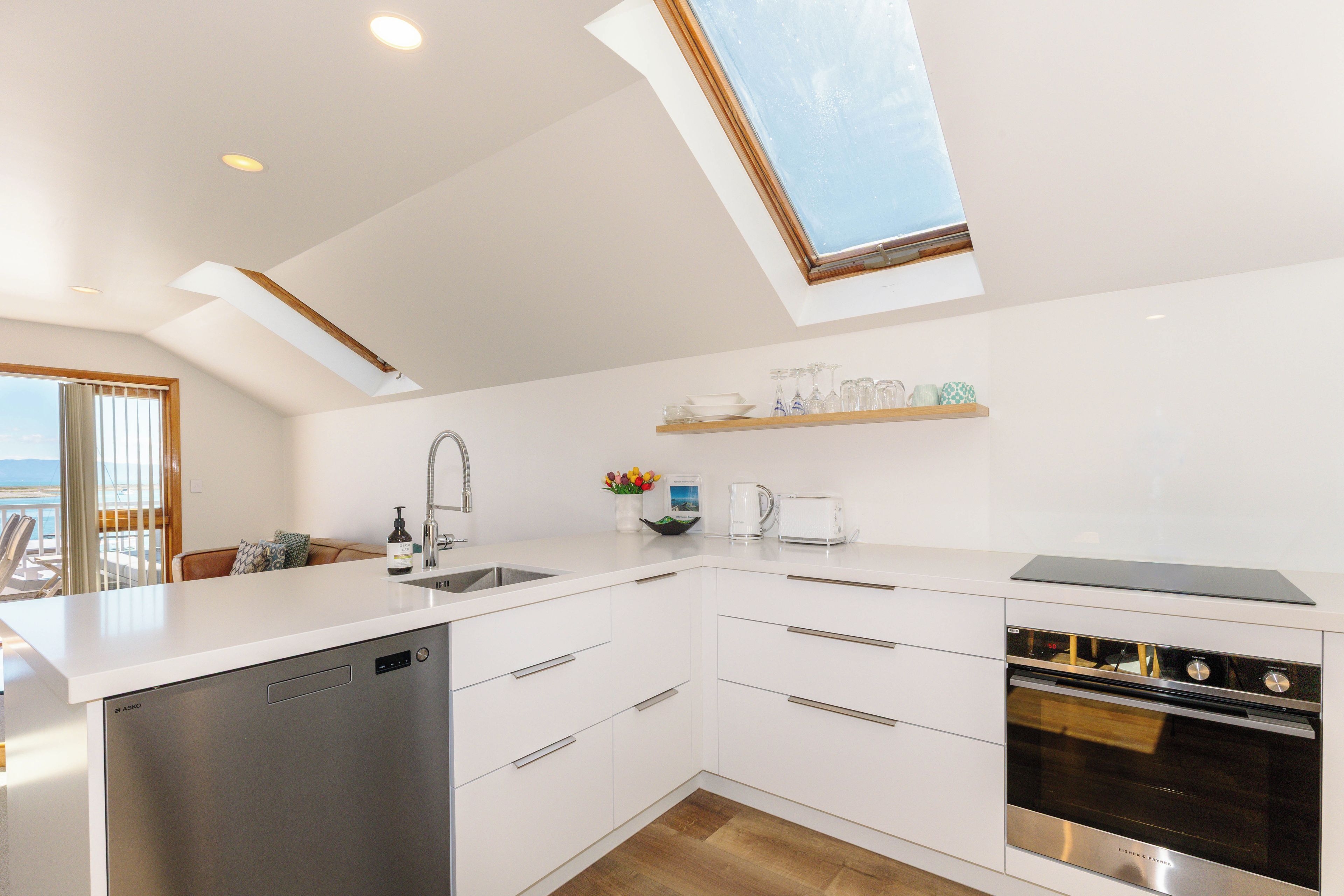 A modern kitchen with white cabinetry, a dishwasher, an oven, and a built-in coffee maker.