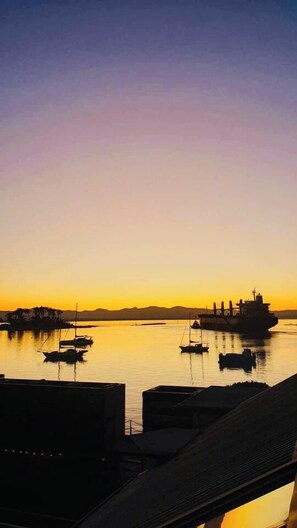 A harbor at sunset with boats and a large ship.