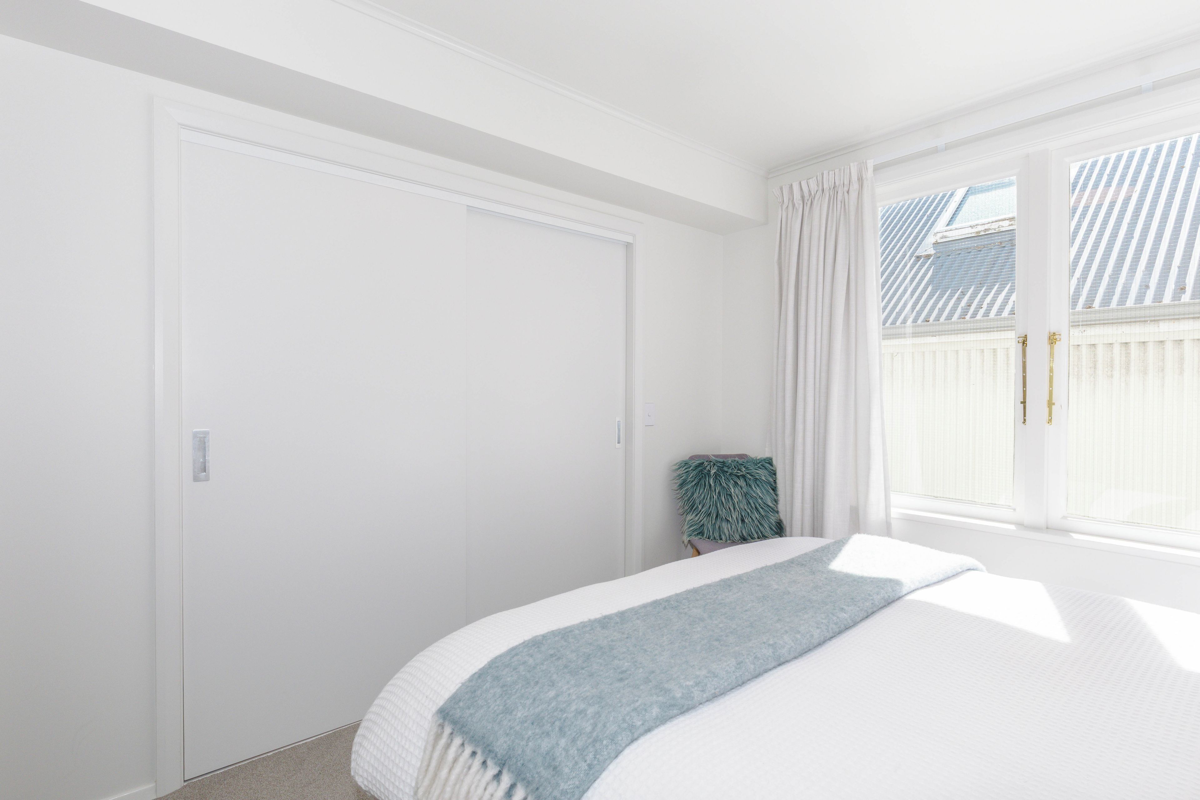 Une chambre à coucher avec un lit, une fenêtre avec des rideaux et une porte.