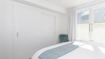 Une chambre à coucher avec un lit, une fenêtre avec des rideaux et une porte.