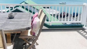A wooden table with chairs on a balcony overlooking a body of water with boats. - Nelson Waterfront | Stunning Harbour Views | 2BR (Nelson)