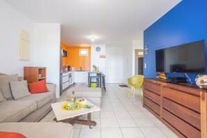 A modern living room with a sofa, coffee table, and a TV on a wooden stand. - Le Cocon de Jojo - Balcon -Climatisation (LE ROBERT)