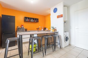 A compact kitchen with a microwave, coffee maker, and a washing machine. - Le Cocon de Jojo - Balcon -Climatisation (LE ROBERT)