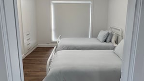 Ein Schlafzimmer mit einem Bett, einem Deckenventilator, einem Fenster und Holzboden.