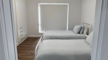 A bedroom with a bed, a ceiling fan, a window, and a wooden floor.
