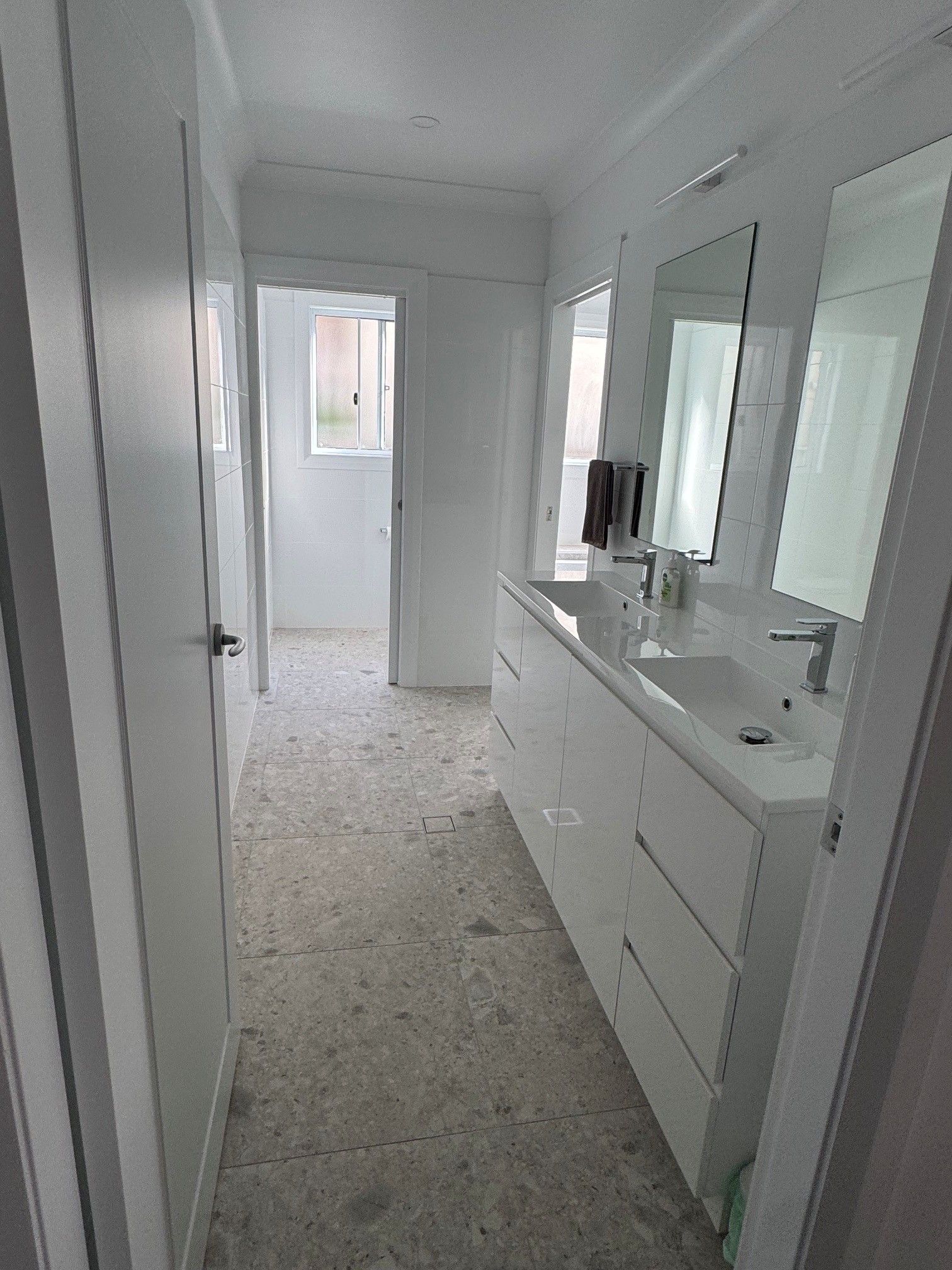 A bathroom with a large mirror, a sink, and a door leading to another room.
