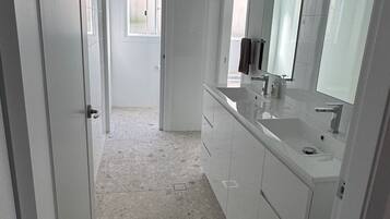 A bathroom with a large mirror, a sink, and a door leading to another room.