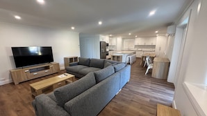Ein modernes Wohnzimmer mit einem großen Ecksofa, einem Flachbildfernseher und einem Holztisch.