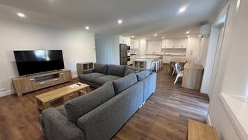 A modern living room with a large sectional sofa, a flat-screen TV, and a wooden coffee table.
