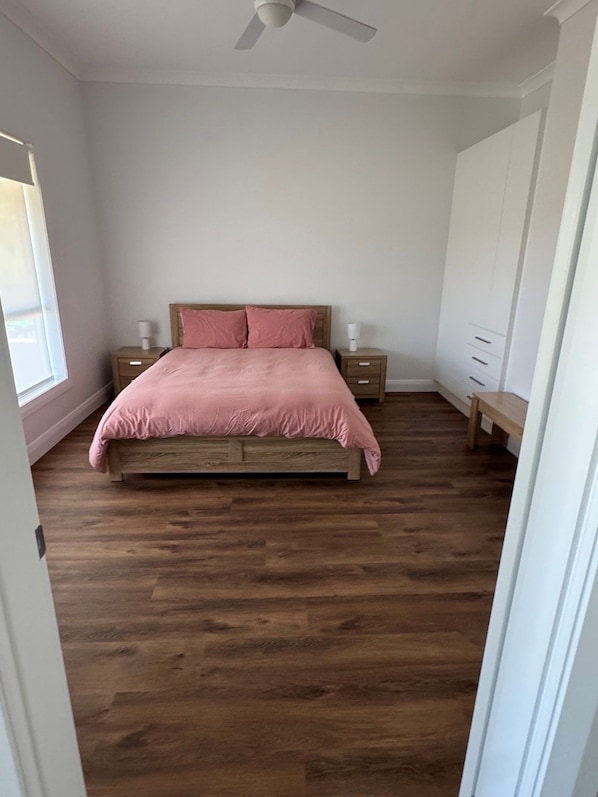 A bedroom with a wooden bed, a nightstand, a dresser, and a ceiling fan.