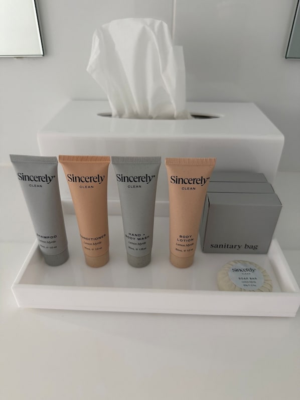 A sanitary bag containing toiletries including shampoo, conditioner, hand and body wash, and soap bar.