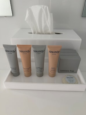 A sanitary bag containing toiletries including shampoo, conditioner, hand and body wash, and soap bar.