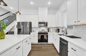 Una cocina moderna con armarios blancos, electrodomésticos de acero inoxidable y piso de madera.