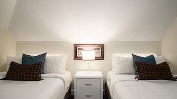 A twin room with two beds, a nightstand with drawers, a framed picture above the nightstand, and a lamp.