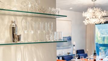A dining area with a glass shelf displaying various glassware, a chandelier, and a table set for dining.