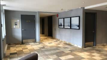 A hotel lobby with a checkered floor, a sofa, a wall-mounted picture, and a door with a sign.