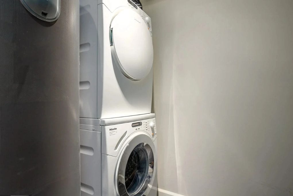 Una lavadora de carga frontal en un cuarto de lavado, con un panel de control y una puerta.