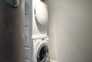 Un lave-linge à chargement frontal, situé dans une buanderie, avec un panneau de commande et une porte.
