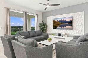 A modern living room with a grey sofa set, a coffee table, and a large landscape painting on the wall. - Lake View Family Escape 2BR Close to Disney (Kissimmee)